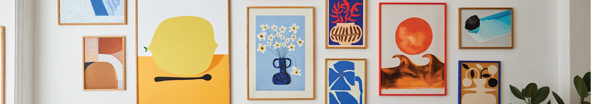 Een galeriewand met verschillende abstracte kunstprints in diverse kleuren en stijlen, waaronder een gele citroen, bloemen in een vaas en geometrische vormen.