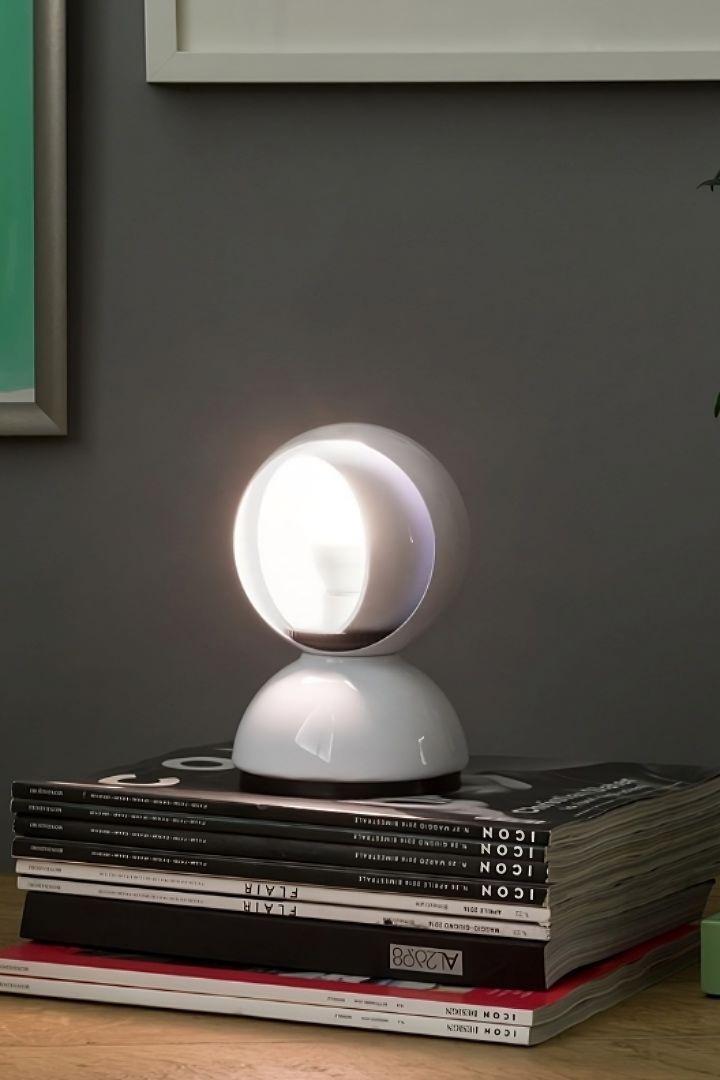 De Eclisse lamp van Artemide staat op een stapel boeken. 