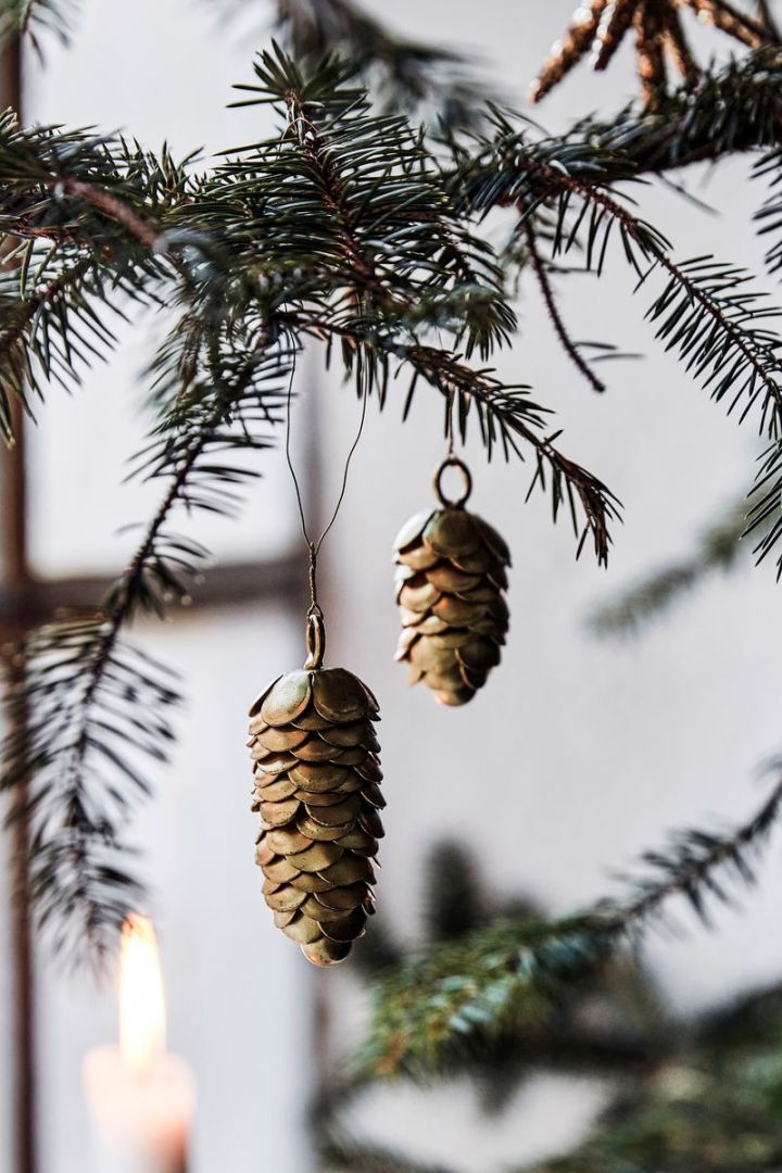 Gebruik op de natuur geïnspireerde kerstboomdecoratie-ideeën zoals de koperen dennenappels van House Doctor. 