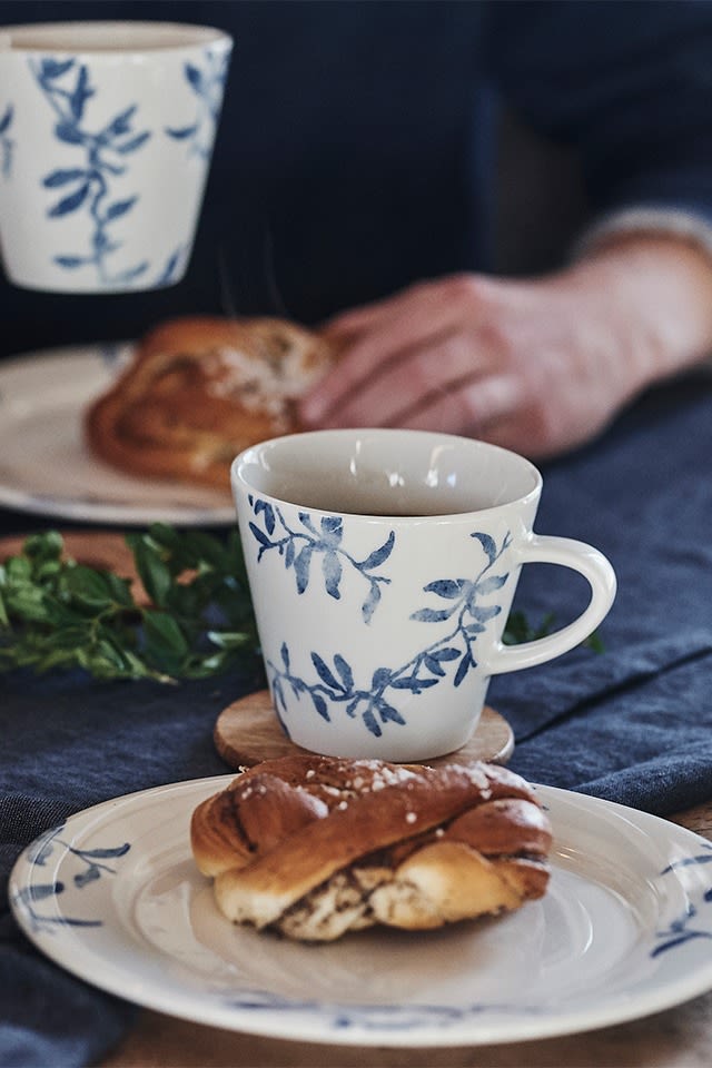 Typisch Zweedse Fika met koffie en een kaneelbroodje, geserveerd op blauw-wit porselein van Scandi Living.