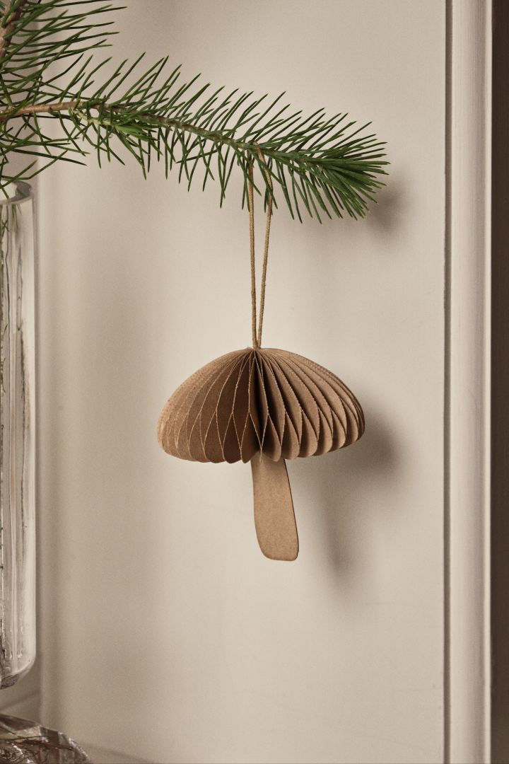 Op de natuur geïnspireerde kerstdecoratie-ideeën zoals de Fungi paddestoeldecoratie van Broste Copenhagen die hier aan een tak hangt.