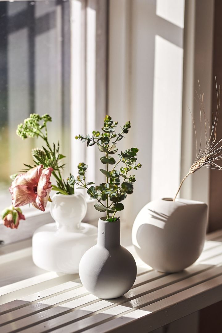 Verschillende kleine vaasjes voor losse bloemen of kleine boeketjes staan op een vensterbank. 