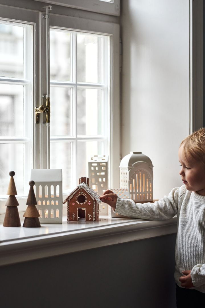 Decoreer met traditionele Scandinavische kerstdecoratie  - De lichthuisjes van Urbania zorgen voor een gezellige sfeer in huis. Hier zie je een verzameling ervan in de vensterbank bij een jongetje. 