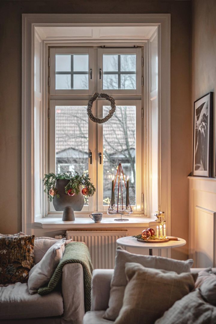 De Zweedse influencer @hannesmauritzson heeft zijn zeer hoge raam versierd met een kerstkrans, de vensterbank is versierd met sparrengroen en de Season Extention kandelaar van Georg Jensen.