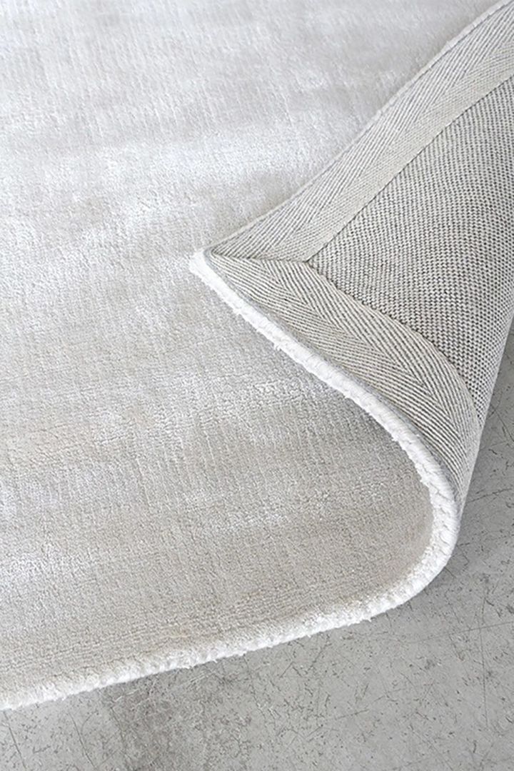 Kies het juiste vloerkleed met behulp van onze vloerkledengids. Hier zie je een close-up van het Solid viscose vloerkleed in de kleur Francis pearl beige van Layered dat je huis een luxueus en warm gevoel geeft.