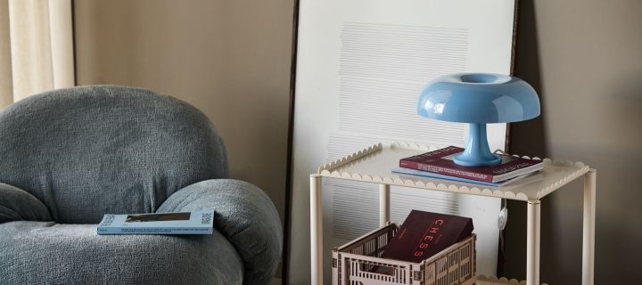 De paddestoellamp Nessino staat verlicht op een bureau met pennen, boeken en een plant. 