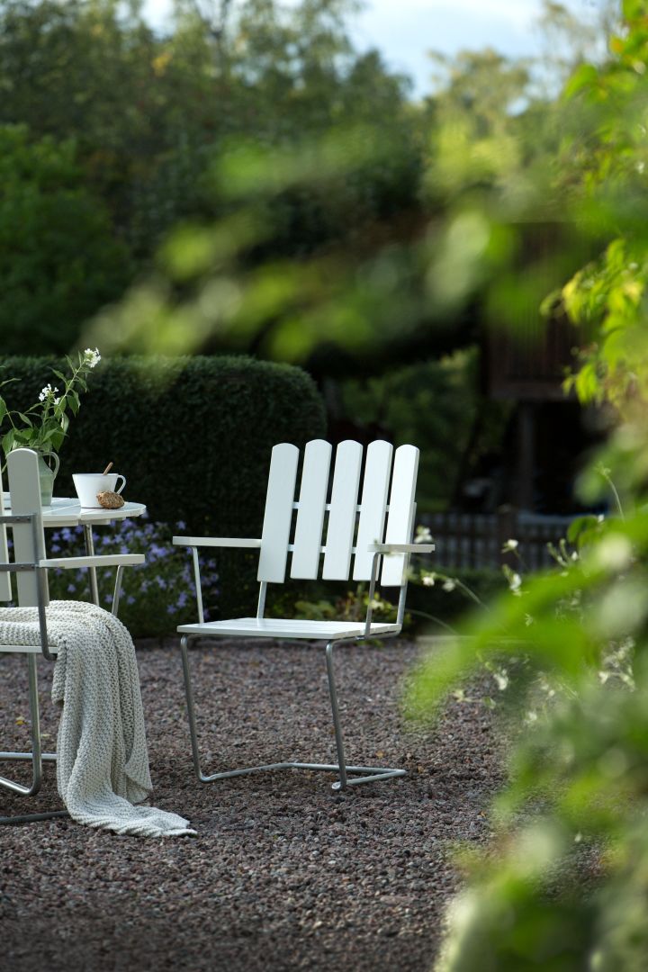 Maak kennis met Grythyttan Stålmöbler, hier A2 fauteuil in wit in de tuin.