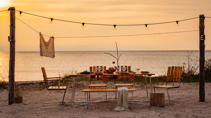 Maak kennis met Grythyttan Stålmöbler, hier A2 stoelen en A1 tafel op het strand bij zonsondergang.