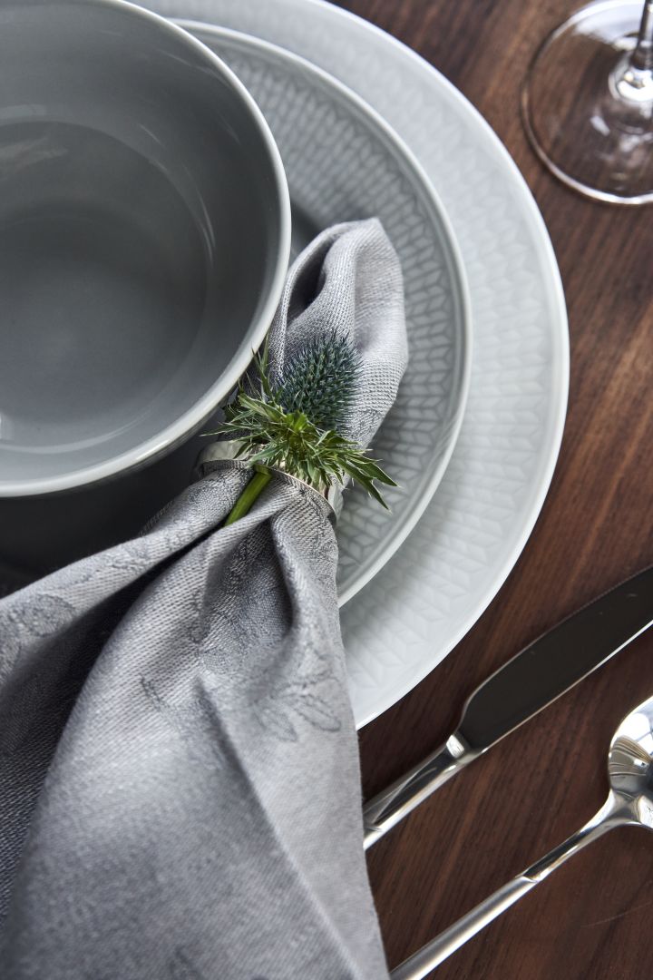 De de tafel met Zweeds Grace porselein in wit en grijs en linnen servet in servetring en met bloem