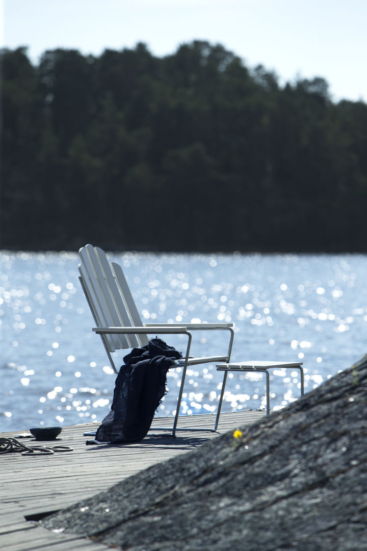 Maak kennis met Grythyttan Stålmöbler, hier een witte fauteuil aan zee.