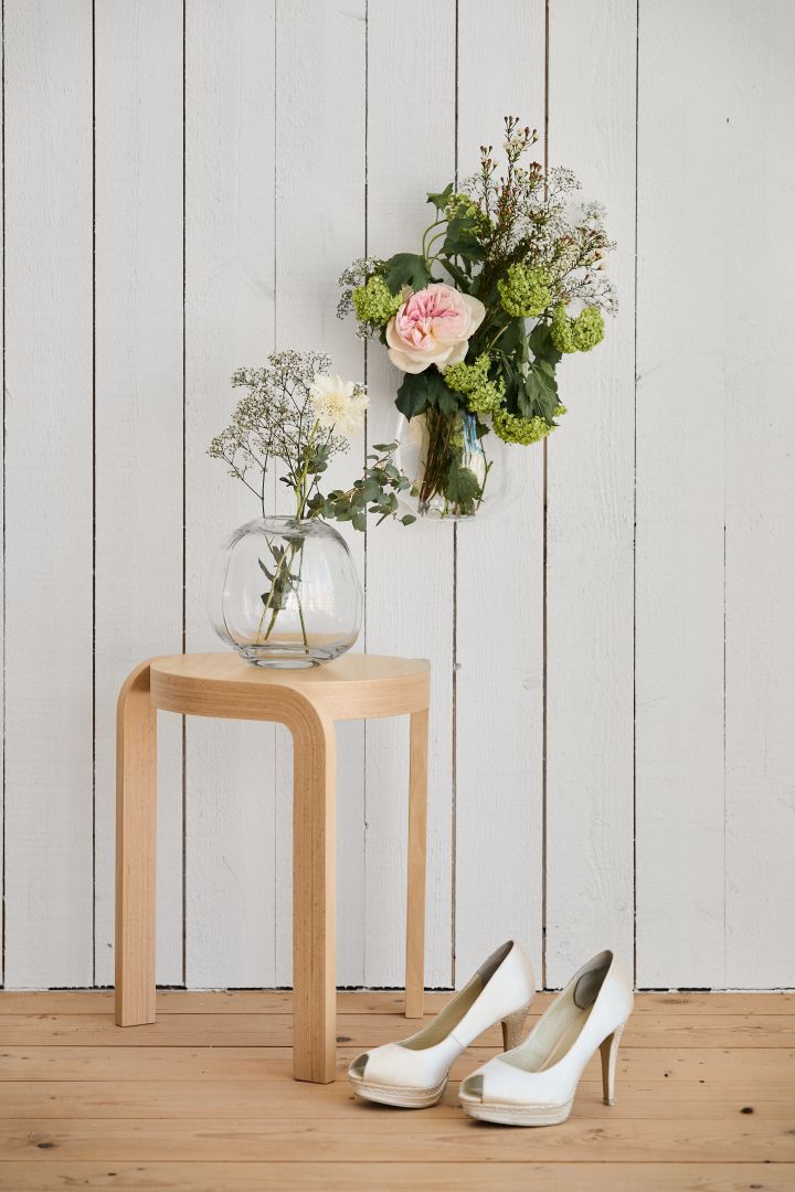 Leg alles vast van je grote dag. Hier zie je een houten Spin kruk van Swedese met daarop bloemen in de Pebble vaas van DBKD. Op de grond staan witte hakken.