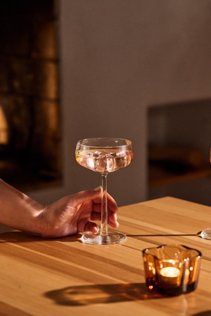 Cadeau-ideeën voor kerst: Hier ziet men een cocktailglas uit de Essence-collectie van Iittala, gevuld met rosé en gepresenteerd op een houten tafel.