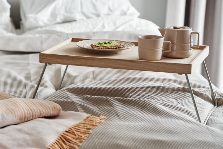 Tactiel beige porselein van NJRD vormt samen met een zachte sprei van gerecycled katoen de perfecte aanvulling op je ontbijt op bed.