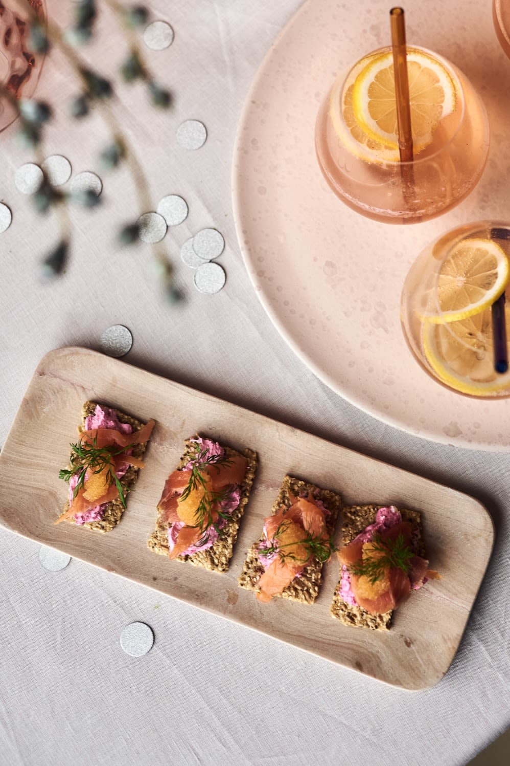 Canapés met zalm en rode biet, een van de eenvoudige voorgerechten voor je nieuwjaarsfeest geserveerd op een stijlvol marmeren dienblad van HK Living samen met een champagnecocktail.