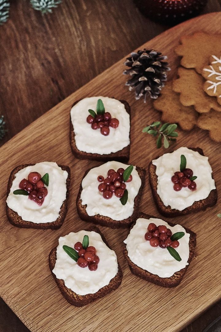 In de afbeelding zie je de afgewerkte zachte peperkoek met romig glazuur en decoraties, prachtig gepresenteerd op een houten plank van Markus Aujalay, vergezeld van een paar koekjes. Perfect voor een Scandinavische kersttraktatie!