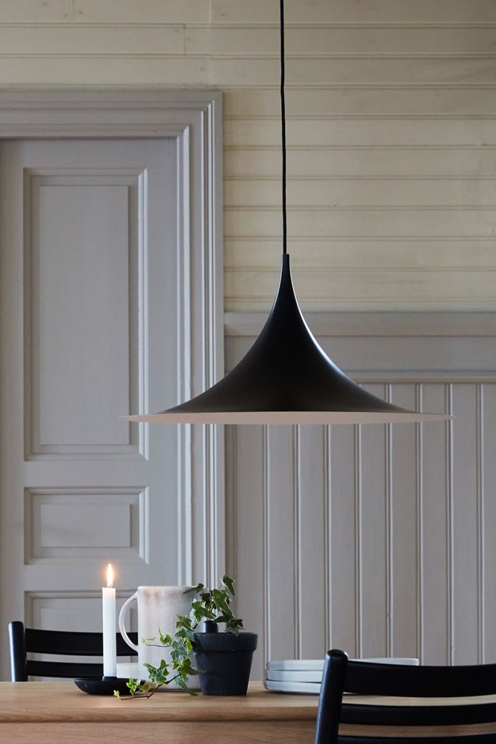 Hier zie je de Scandinavische designlamp Semi van Gubi boven een eettafel hangen.