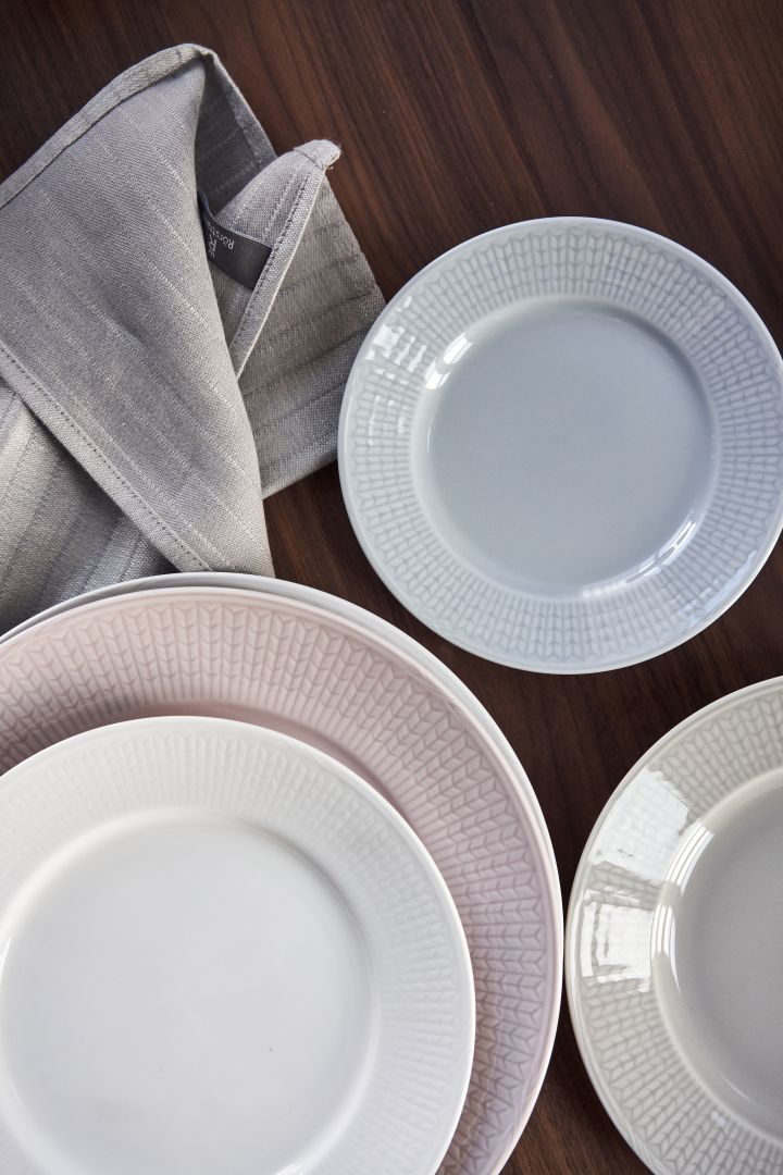 Zweedse Grace borden in wit, roze, blauw en grijs op een donkere houten tafel. 