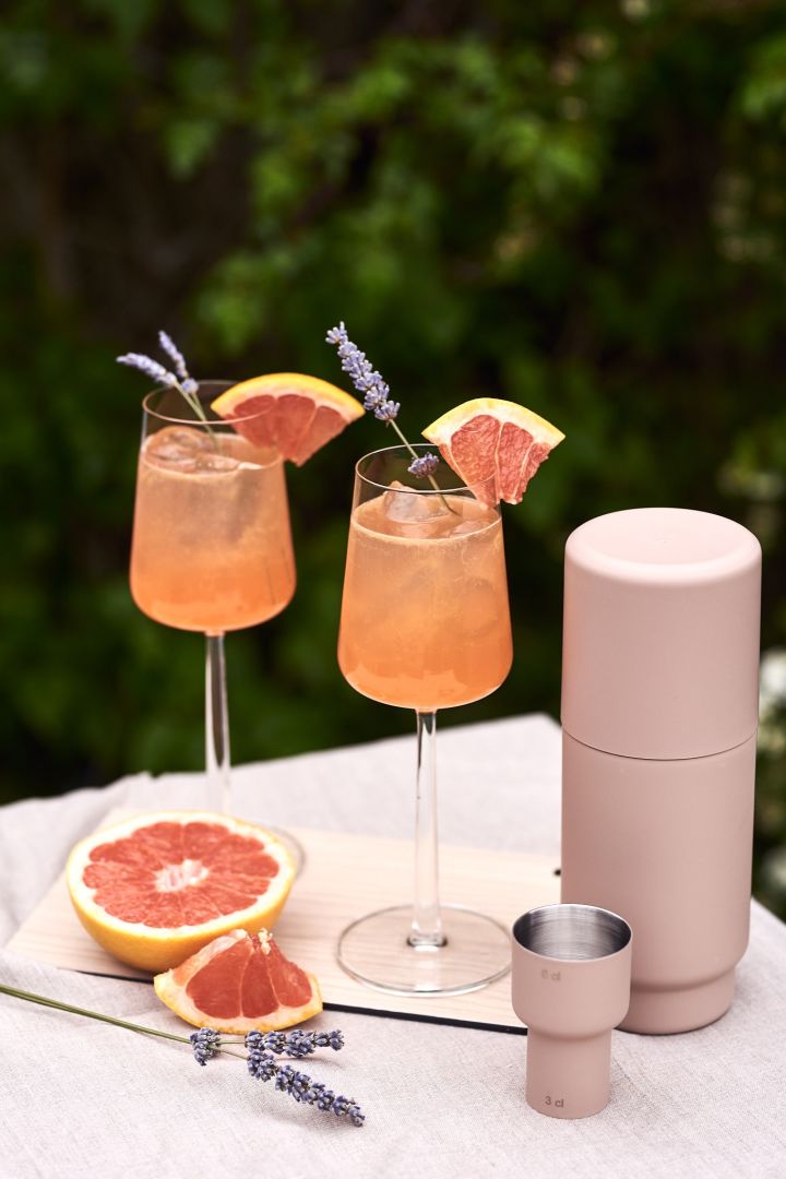 Grapefruitdrank met lavendeltakje is een van de eenvoudige zomerdrankjes die we deze zomer proberen - hier geserveerd in een wit wijnglas.