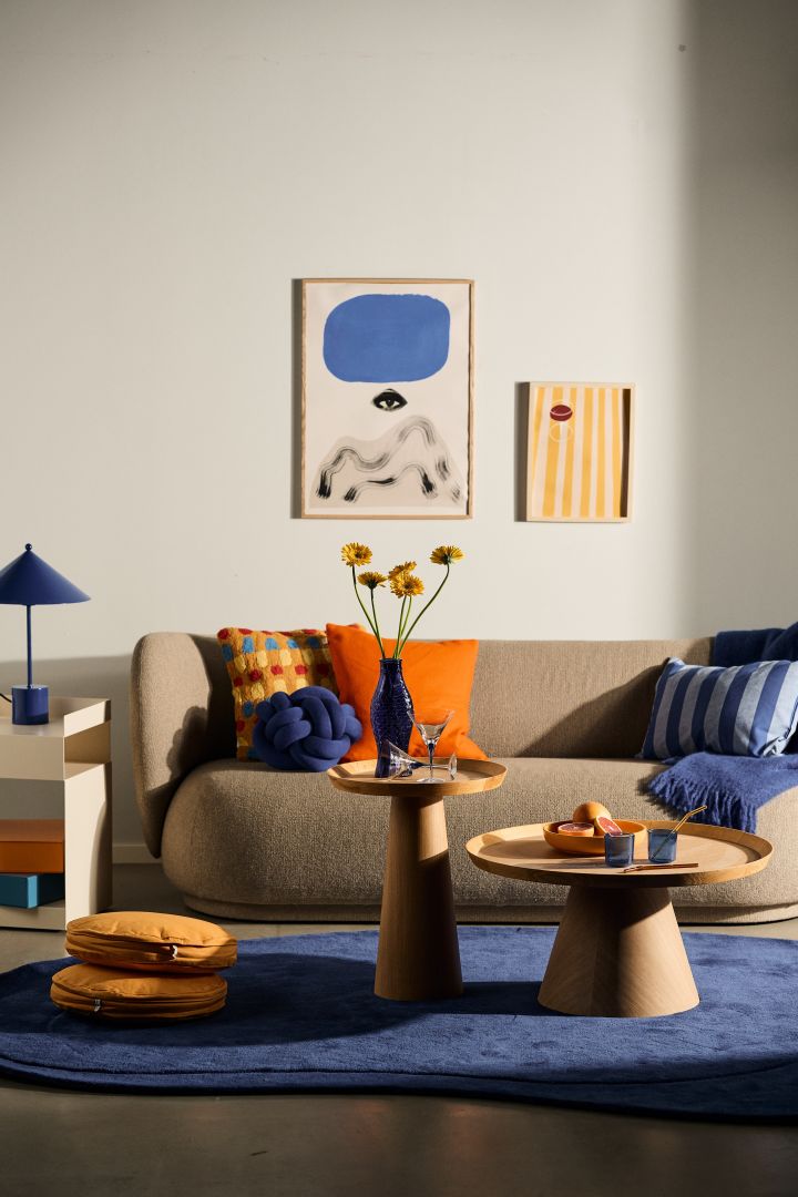 Richt in volgens de Scandinavische interieurtrends in 2024 en gebruik veel kleuren en patronen om te mixen & matchen. Dit is een woonkamer met een blauw, oranje en geel decor. 