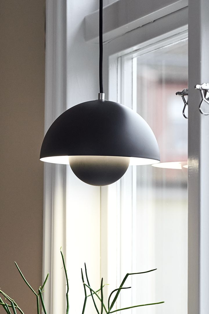 Hier zie je een Scandinavische designlamp, de Flowerpot VP1 van &Tradition, in een raam hangen.