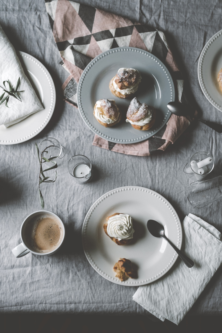 Hier zie je @kohlundkimchi's Semlor op tafel staan op verschillende gekleurde borden uit de Dots collectie van Scandi Living, samen met een kopje koffie.