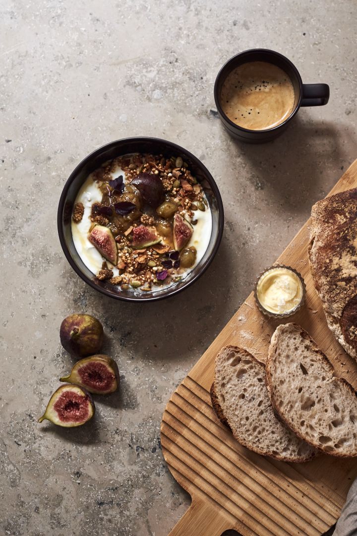 De bruine kom uit de Lines serie van NJRD met muesli, een kopje koffie en een houten plank met gesneden brood erop.