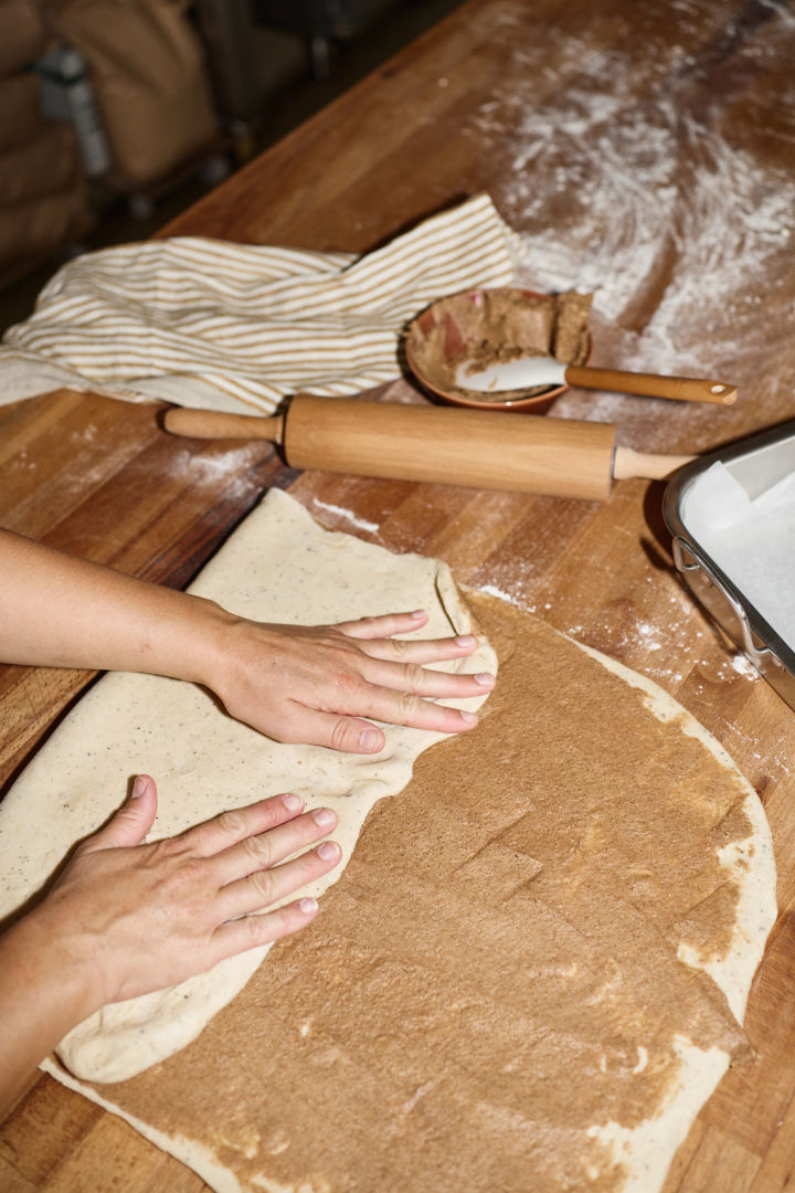 Voor Zweedse kaneelbroodjes moet het deeg eerst worden uitgerold en dan worden ingesmeerd met de boter- en suikervulling, waarna het deeg twee keer wordt gevouwen, zoals je hier kunt zien.